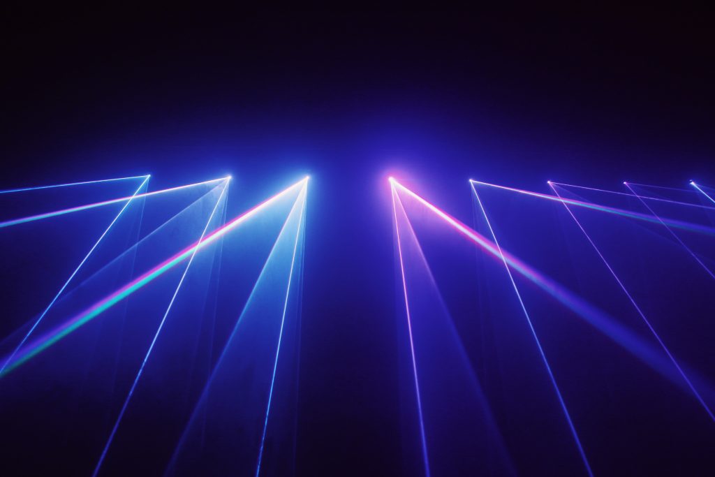 Bright blue and purple lasers emitting from a dark background